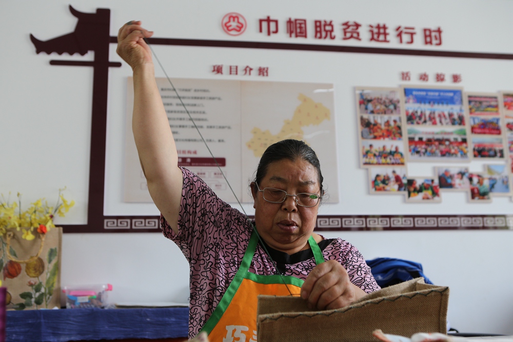 3、坪坝村65岁的残疾村民胡先祥在缝制手工产品.JPG
